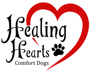 Logo with the words "Healing Hearts Comfort Dogs" in black script. A red heart surrounds the text, with a black paw print replacing the dot over the letter "i" in "Healing.